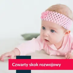 Niemowlę w różowej opasce z kokardką leży na brzuchu, patrząc w bok.